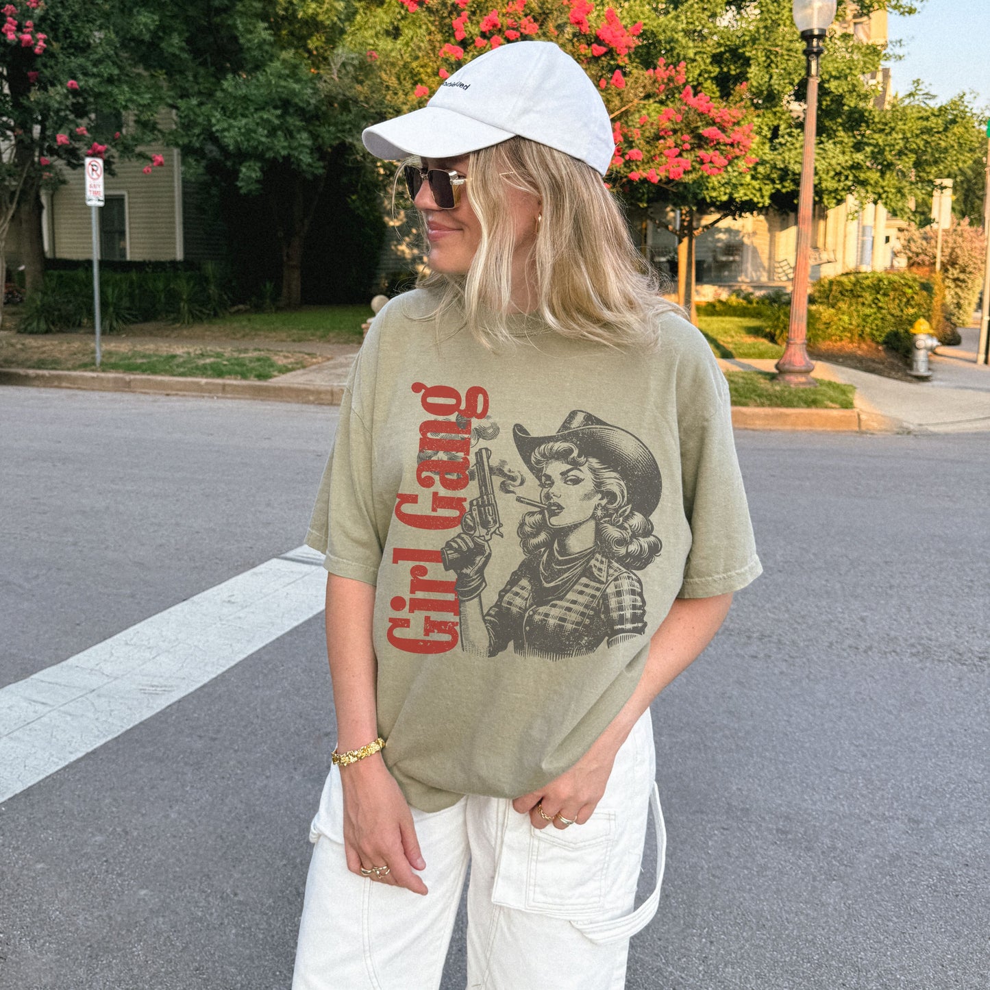 Person wearing a graphic t-shirt with a design and text, standing on a street.