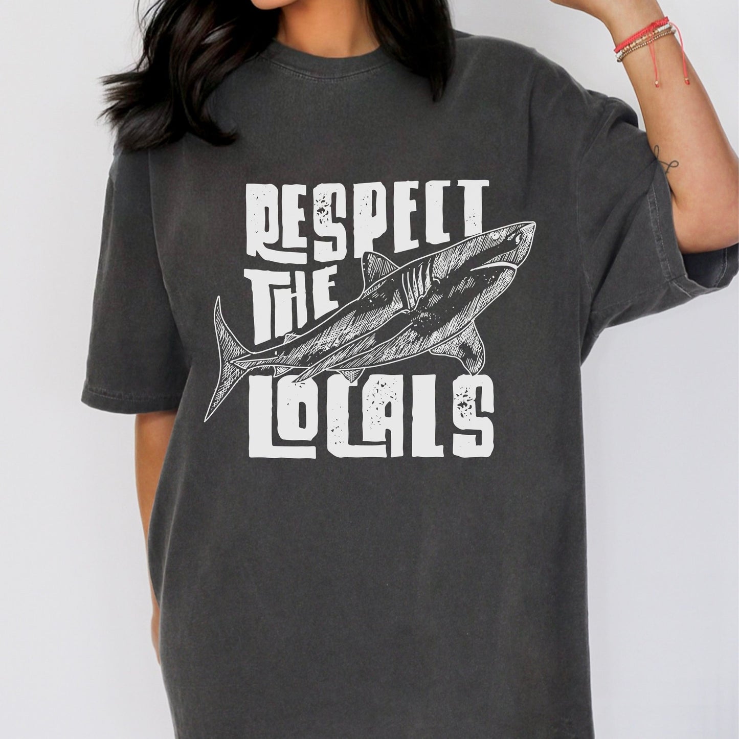 Vintage beach t-shirt featuring a shark print and "Respect the Locals" text. Perfect ocean conservation shirt for surfers, nature lovers, and coastal lifestyle fans. Unisex graphic tee with laid-back retro style.
