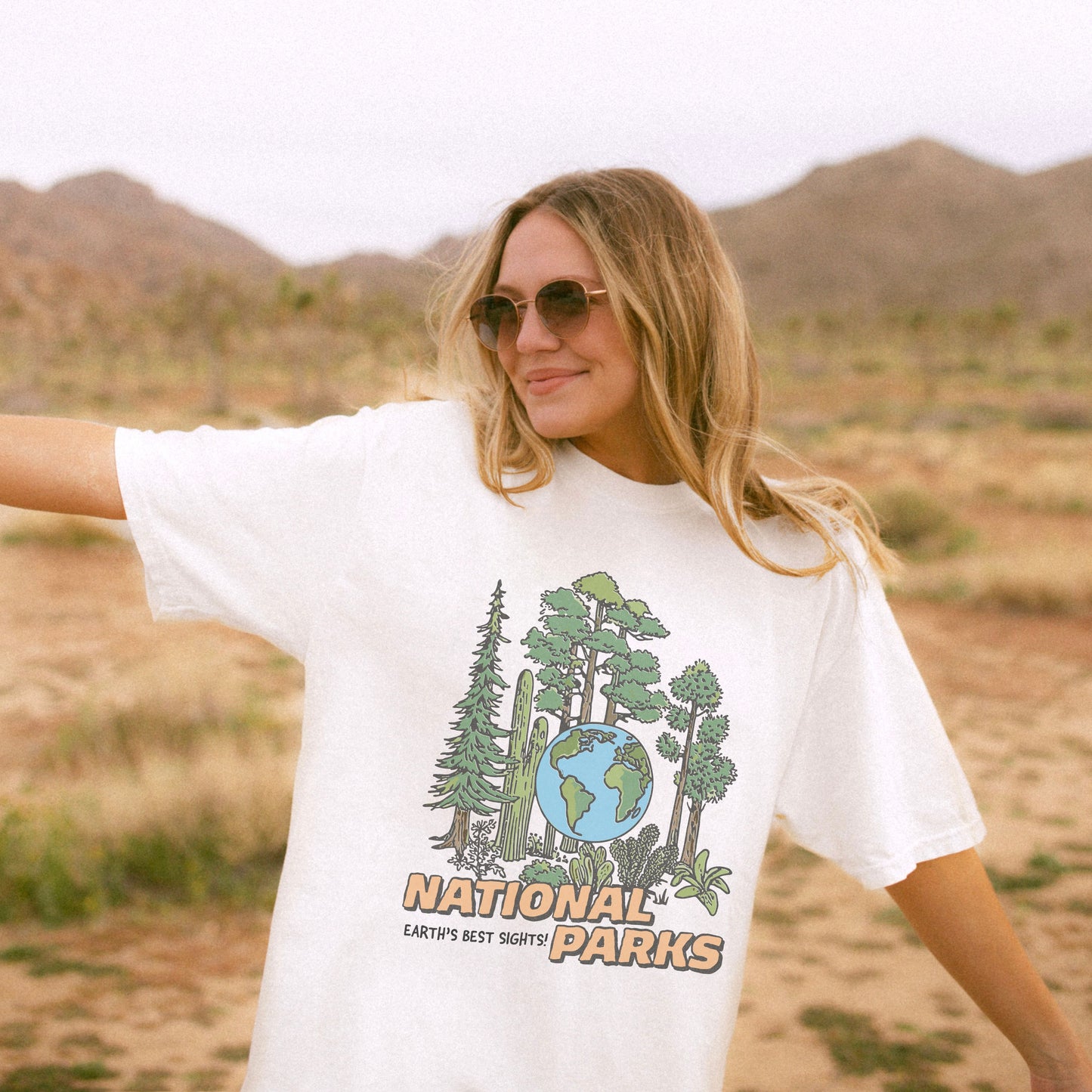 Woman wearing a white t-shirt with a national parks graphic in a desert setting