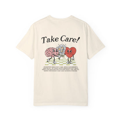 Graphic tee featuring a whimsical design with a heart and brain holding a flower, paired with motivational text encouraging self-care and positivity. Perfect for mental health awareness and retro-inspired casual style.
