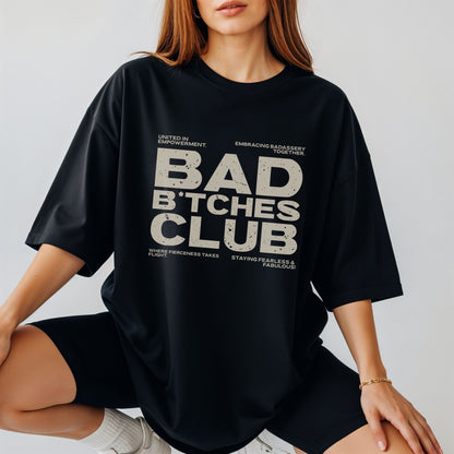 Person wearing a black t-shirt with 'BAD B*TCHES CLUB' text on a plain background