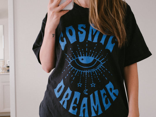 Mystical graphic tee featuring a spiritual eye, cosmic dreamer typography, and celestial design. Perfect for vintage-inspired outfits, boho rebel style, and night sky aesthetics.