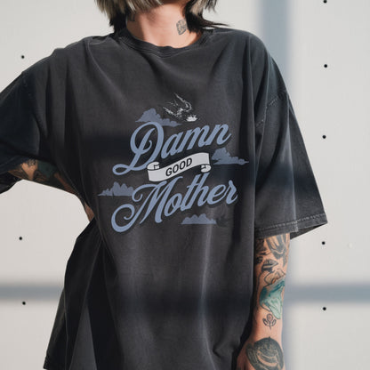 T-shirt with "Damn Good Mother" design in vintage tattoo style. Retro mama t shirt with bold mom statement and bird illustrations. Cool mom graphic tee perfect for Mother’s Day gift or everyday wear. Trendy mom gift tee with edgy mom tee shirt vibes. Stylish mom shirt for confident, fun-loving mamas. Unique cute mom saying tee with rad mama energy. Tattoo style mom tee that makes the perfect bold mom statement piece.