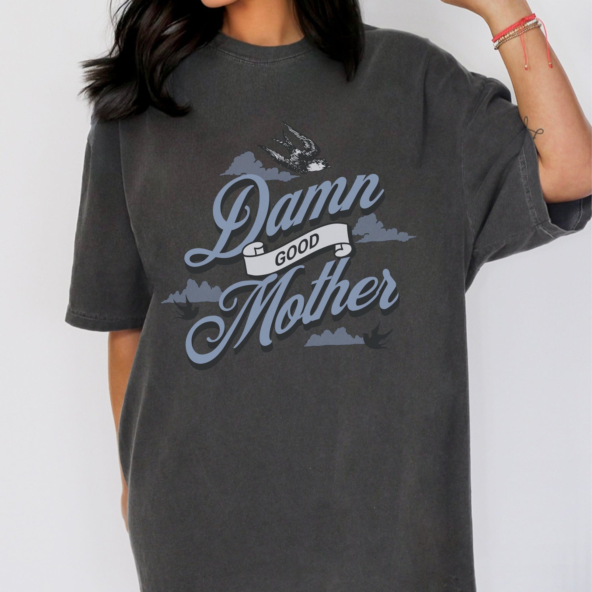 T-shirt with "Damn Good Mother" design in vintage tattoo style. Retro mama t shirt with bold mom statement and bird illustrations. Cool mom graphic tee perfect for Mother’s Day gift or everyday wear. Trendy mom gift tee with edgy mom tee shirt vibes. Stylish mom shirt for confident, fun-loving mamas. Unique cute mom saying tee with rad mama energy. Tattoo style mom tee that makes the perfect bold mom statement piece.