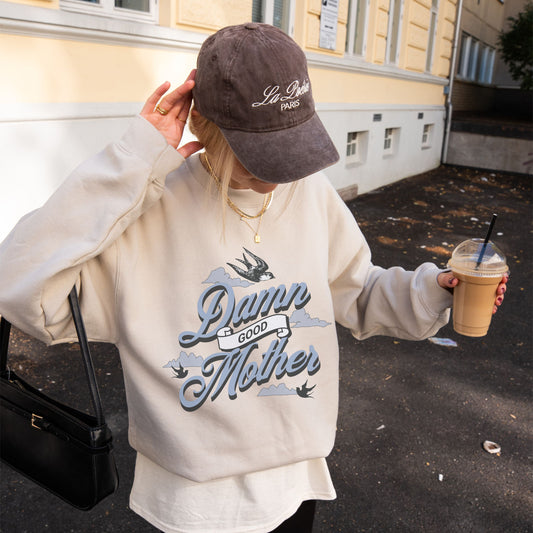 Crewneck sweatshirt with “Damn Good Mother” graphic in tattoo style. Cool mom sweatshirt with vintage and retro mama sweater vibe. Bold mom pullover for edgy, confident women. Funny mom jumper and trendy mom sweater perfect for gifting or everyday wear. Stylish mama crew with rad mom graphic top. Great for Mother's Day crewneck gift or casual looks. Cute mom sweatshirt with bold statement and timeless design.