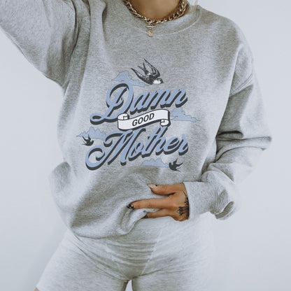 Crewneck sweatshirt with “Damn Good Mother” graphic in tattoo style. Cool mom sweatshirt with vintage and retro mama sweater vibe. Bold mom pullover for edgy, confident women. Funny mom jumper and trendy mom sweater perfect for gifting or everyday wear. Stylish mama crew with rad mom graphic top. Great for Mother's Day crewneck gift or casual looks. Cute mom sweatshirt with bold statement and timeless design.
