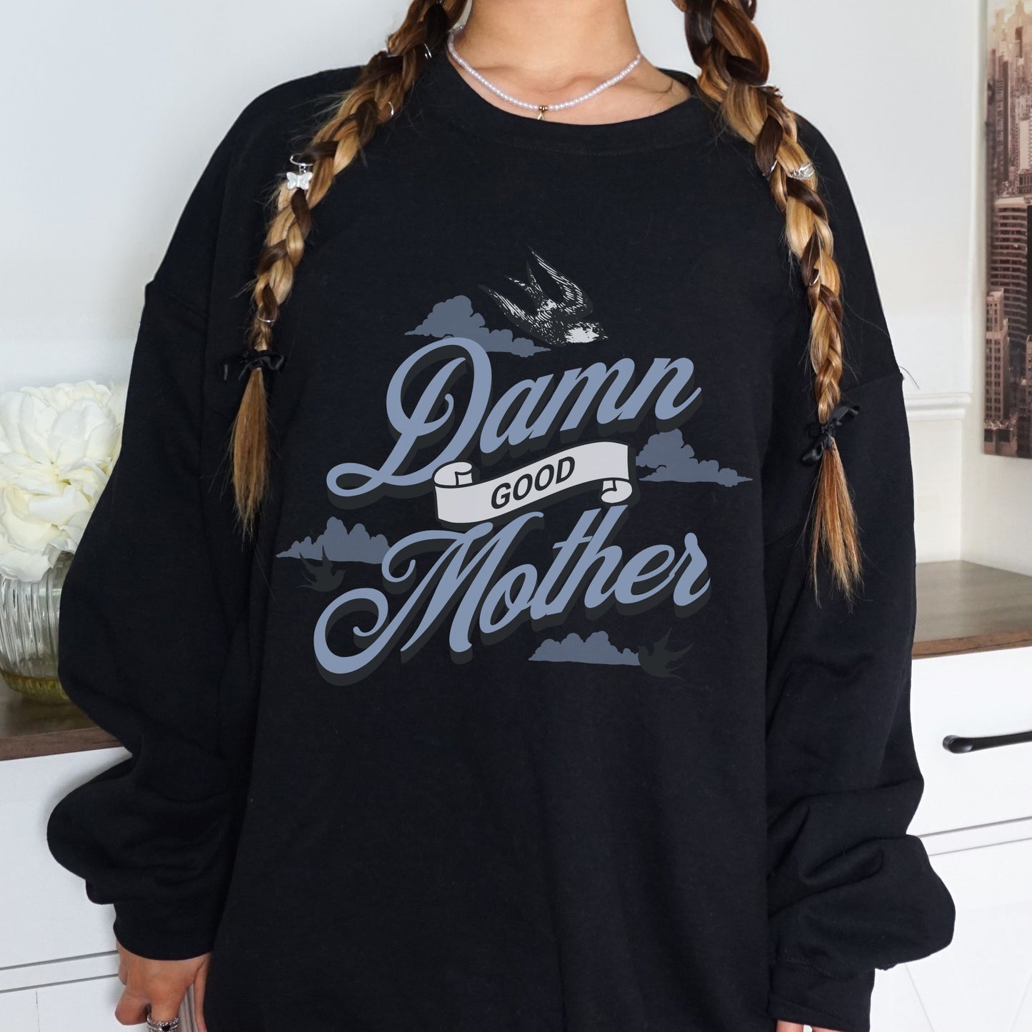 Crewneck sweatshirt with “Damn Good Mother” graphic in tattoo style. Cool mom sweatshirt with vintage and retro mama sweater vibe. Bold mom pullover for edgy, confident women. Funny mom jumper and trendy mom sweater perfect for gifting or everyday wear. Stylish mama crew with rad mom graphic top. Great for Mother's Day crewneck gift or casual looks. Cute mom sweatshirt with bold statement and timeless design.