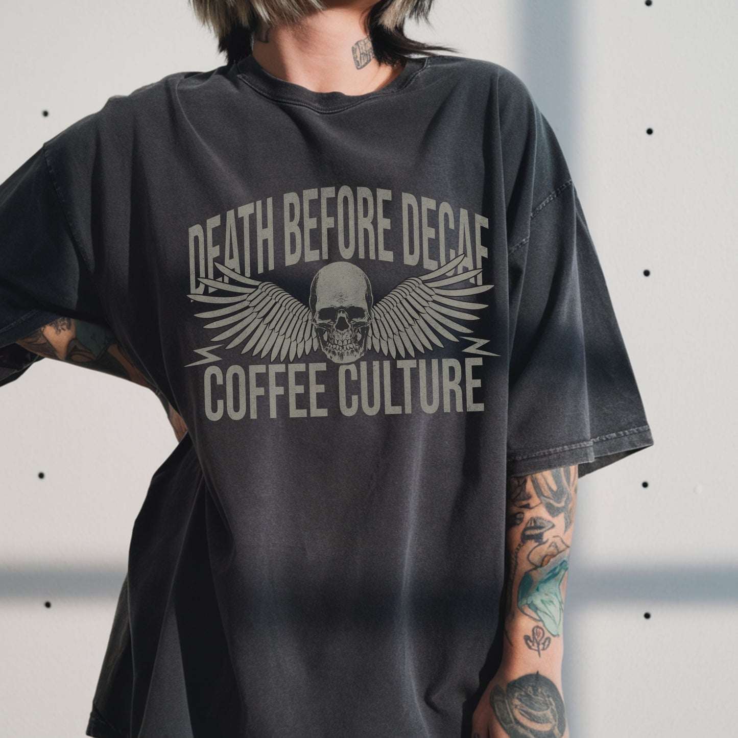 T-shirt with bold Death Before Decaf design featuring a skull and wings. Perfect for coffee lovers who prefer strong brews. This edgy coffee skull shirt makes a great caffeine addict tee or anti decaf shirt. Fits unisex style and works as a vintage coffee tee, goth coffee shirt, or strong coffee shirt. Ideal for casual wear, gifting, or making a bold coffee culture statement. Funny coffee shirt with attitude.