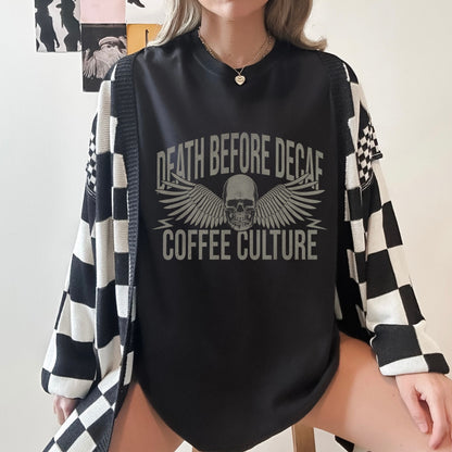 T-shirt with bold Death Before Decaf design featuring a skull and wings. Perfect for coffee lovers who prefer strong brews. This edgy coffee skull shirt makes a great caffeine addict tee or anti decaf shirt. Fits unisex style and works as a vintage coffee tee, goth coffee shirt, or strong coffee shirt. Ideal for casual wear, gifting, or making a bold coffee culture statement. Funny coffee shirt with attitude.