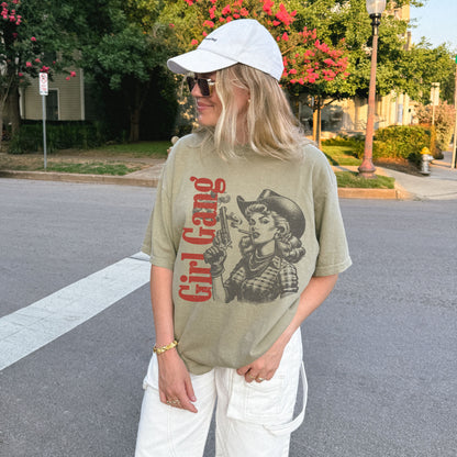 Person wearing a graphic t-shirt with a design and text, standing on a street.