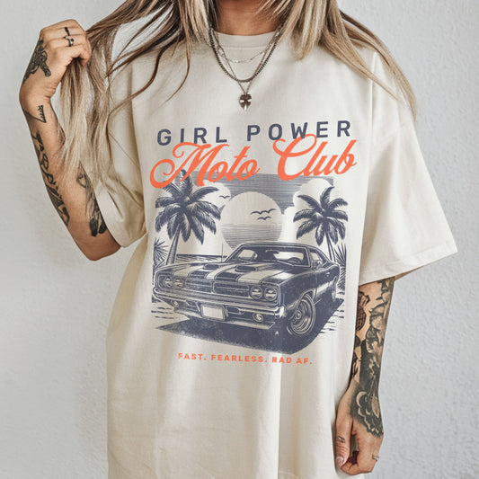 Person wearing a 'Girl Power Moto Club' t-shirt with a graphic of a car and palm trees.
