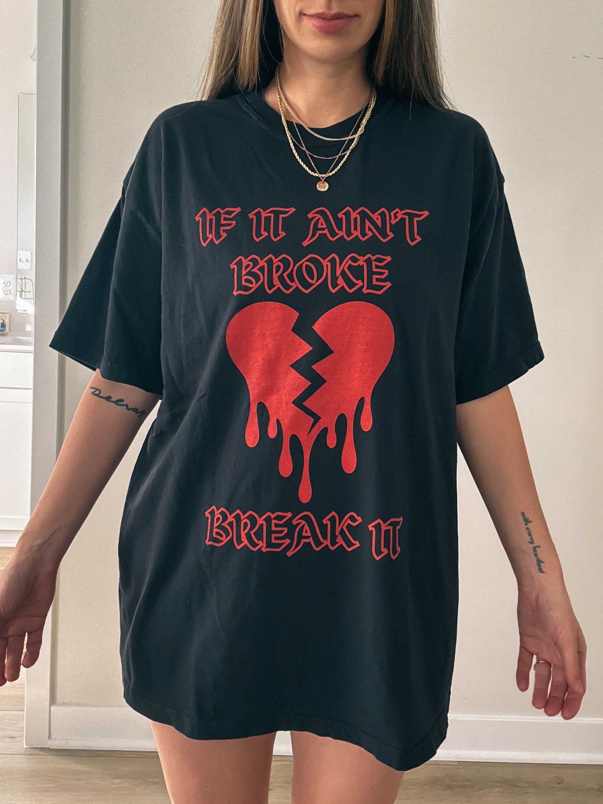 T-shirt with bold gothic-style text 'If It Ain't Broke, Break It' and dripping broken heart graphic. Perfect for rebellious fashion, Valentine’s Day outfit ideas, edgy streetwear style, and bold statement graphic tees.
