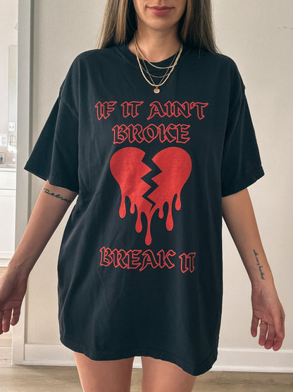 T-shirt with bold gothic-style text 'If It Ain't Broke, Break It' and dripping broken heart graphic. Perfect for rebellious fashion, Valentine’s Day outfit ideas, edgy streetwear style, and bold statement graphic tees.