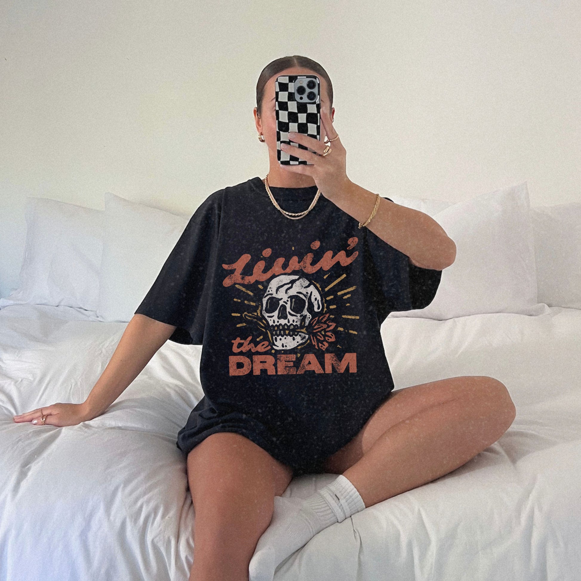 Black t-shirt with a vintage skull graphic, sunburst design, and 'Livin' the Dream' text in retro font. Perfect for a retro skull t-shirt or distressed skull tee look with a boho rocker vibe. Casual vintage t-shirt style for edgy everyday wear.