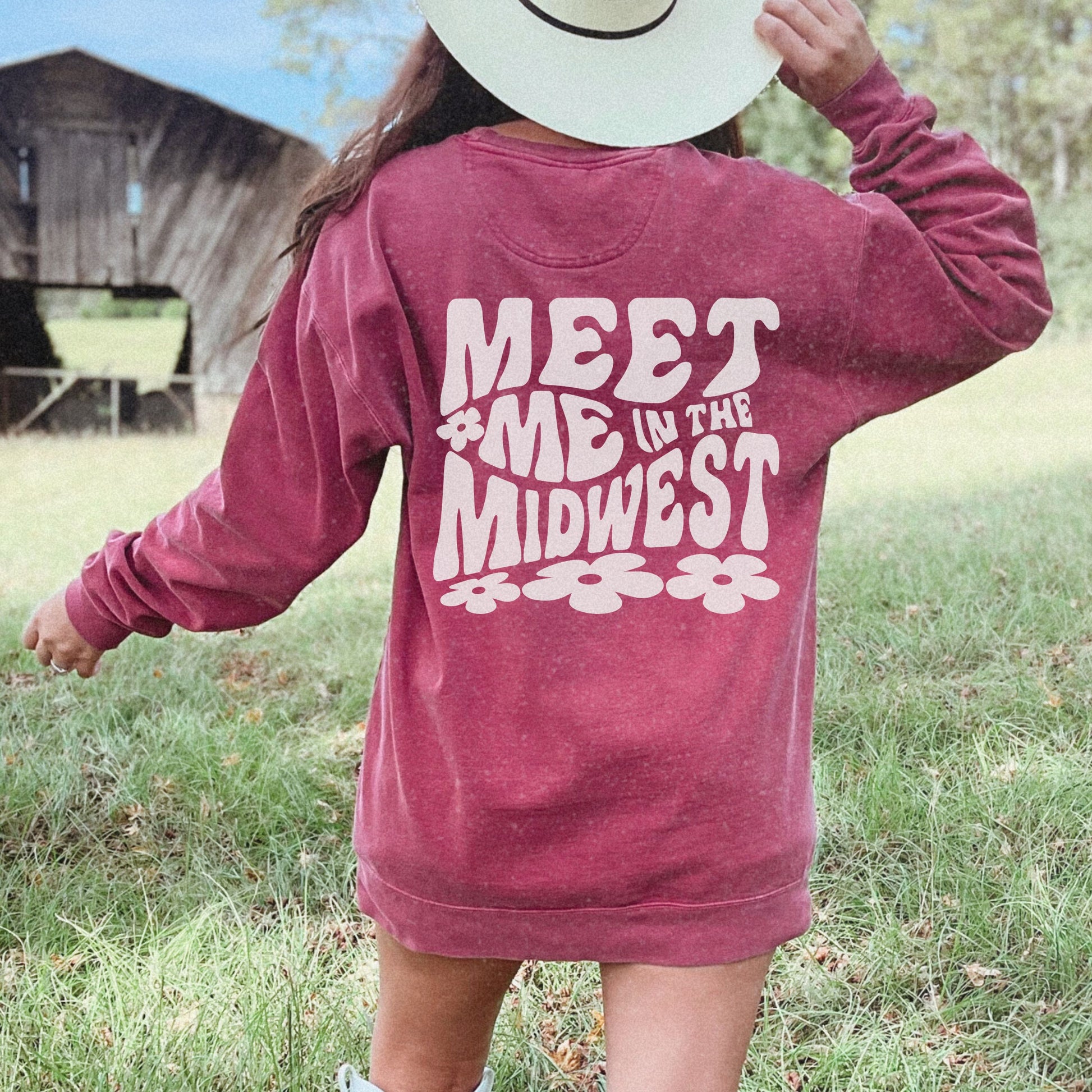 Crewneck sweatshirt with bold "Meet Me in the Midwest" typography and floral design. Perfect for casual outfits, relaxed weekends, or road trips. Oversized fit offers trendy, comfortable style for everyday wear.