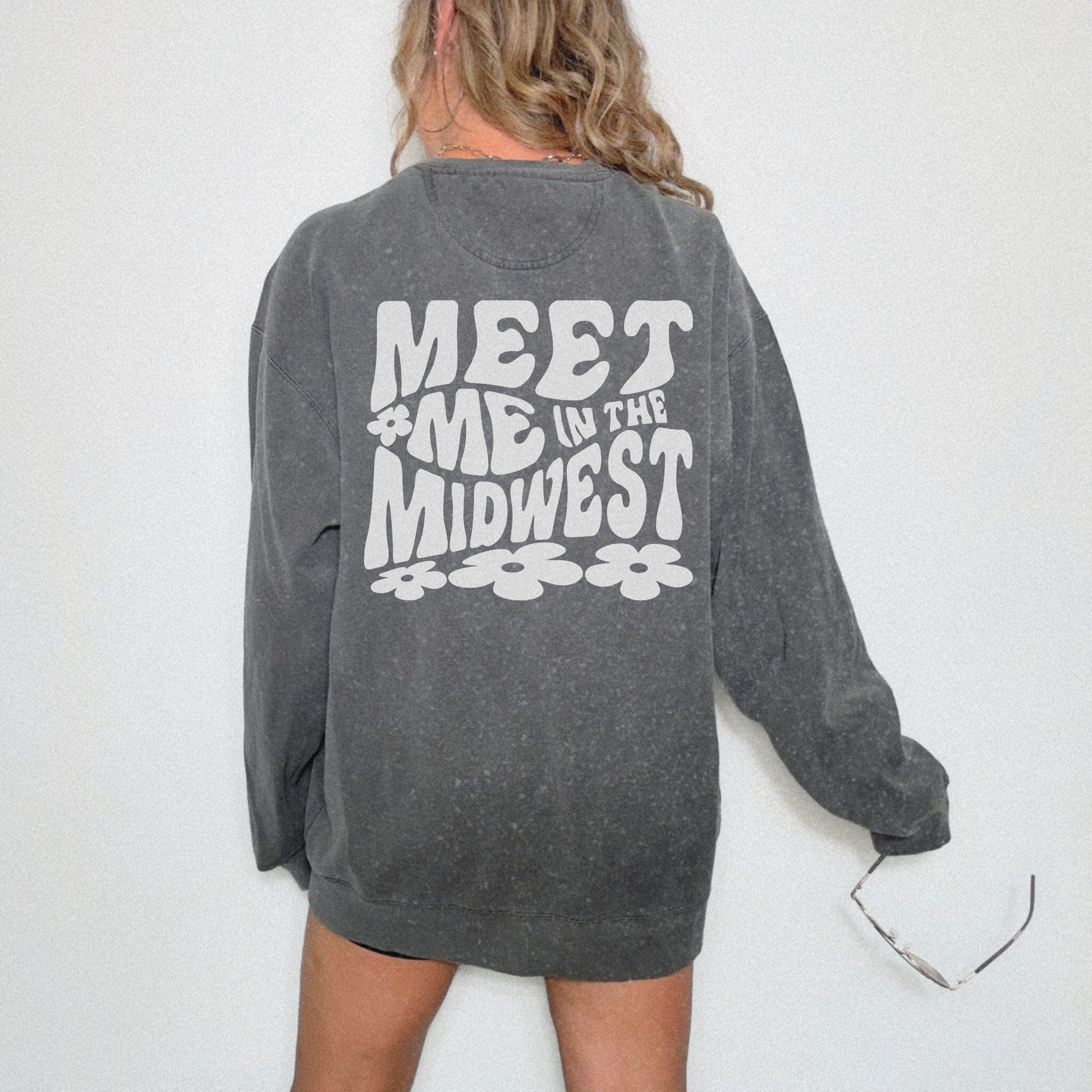Crewneck sweatshirt with bold "Meet Me in the Midwest" typography and floral design. Perfect for casual outfits, relaxed weekends, or road trips. Oversized fit offers trendy, comfortable style for everyday wear.