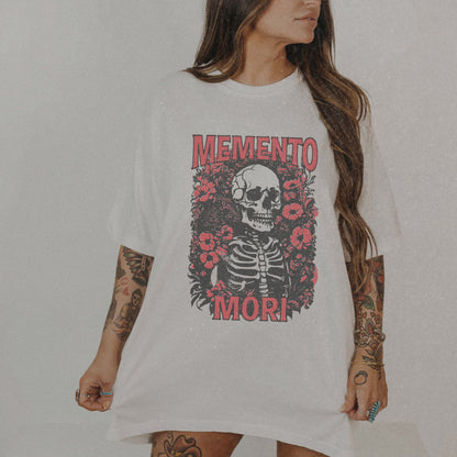 Graphic tee featuring a detailed skull design surrounded by floral elements, perfect for fans of vintage skeleton tees, gothic skull shirts, and retro goth style. A trendy death-themed shirt combining dark floral and skeleton art for casual or streetwear looks.