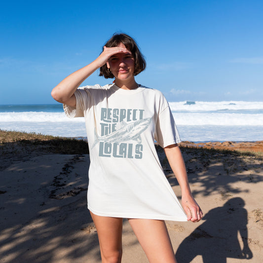 Vintage beach t-shirt featuring a shark print and "Respect the Locals" text. Perfect ocean conservation shirt for surfers, nature lovers, and coastal lifestyle fans. Unisex graphic tee with laid-back retro style.