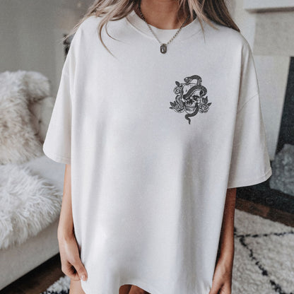 Snake skull shirt with a bold skull, rose, and snake design, blending edgy and gothic vibes. This dark graphic tee is ideal for fans of retro snake shirts, witchy skeleton tees, or unique rose t-shirts seeking a vintage gothic aesthetic for everyday wear.