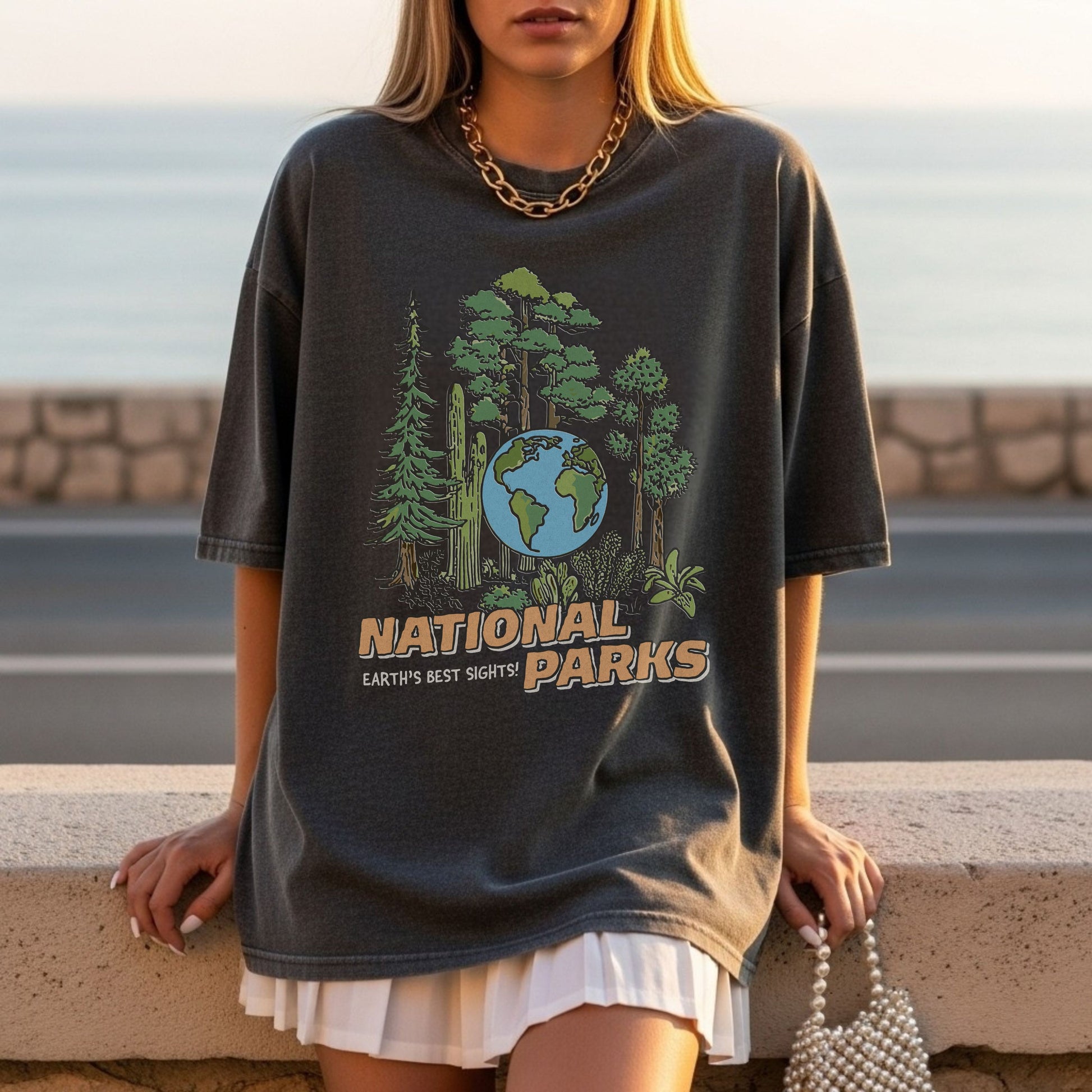 Person wearing a black t-shirt with 'National Parks' graphic design by the sea.