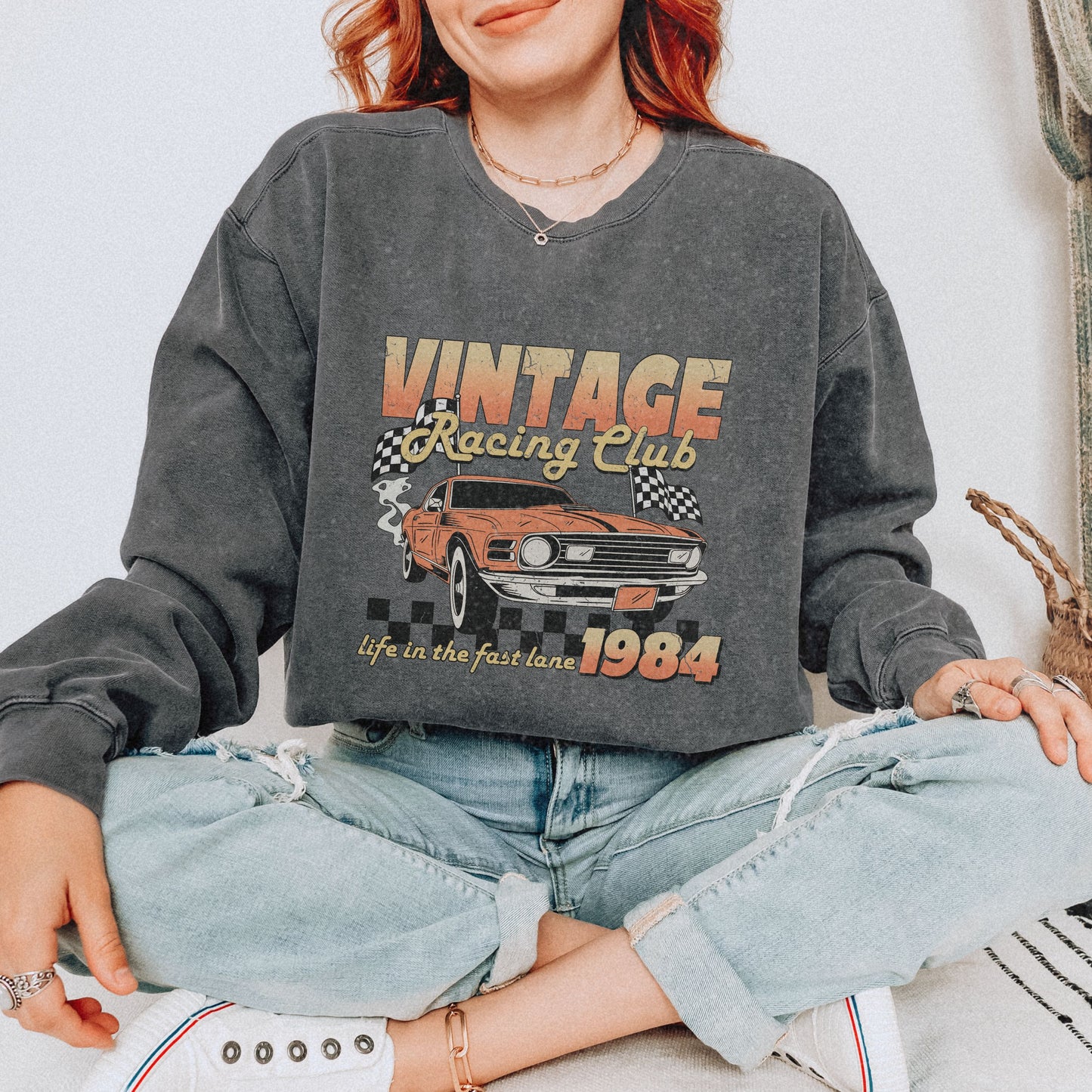 Retro car club shirt with vintage 1984 race car graphic, distressed design, and checkered flag accents. Perfect for muscle car lovers and fans of classic racing. Available as a crewneck sweatshirt in multiple colors.