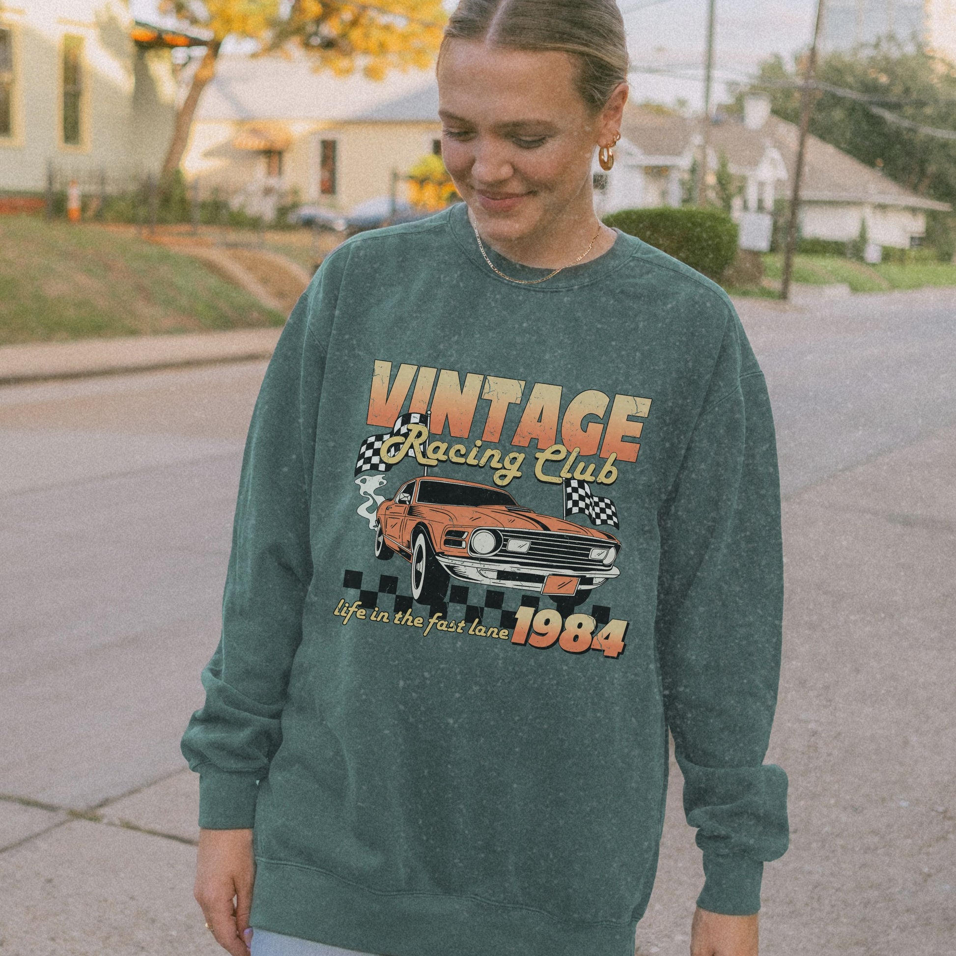 Retro car club shirt with vintage 1984 race car graphic, distressed design, and checkered flag accents. Perfect for muscle car lovers and fans of classic racing. Available as a crewneck sweatshirt in multiple colors.