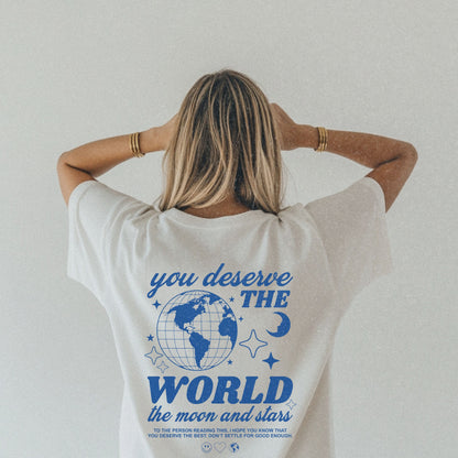 Motivational graphic t-shirt with a celestial design featuring stars, moon, and globe. Includes the inspiring phrase 'you deserve the world.' A trendy and stylish vintage-inspired tee for casual wear, perfect for spreading positivity and empowerment.