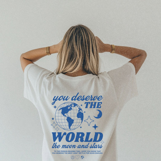 Motivational graphic t-shirt with a celestial design featuring stars, moon, and globe. Includes the inspiring phrase 'you deserve the world.' A trendy and stylish vintage-inspired tee for casual wear, perfect for spreading positivity and empowerment.
