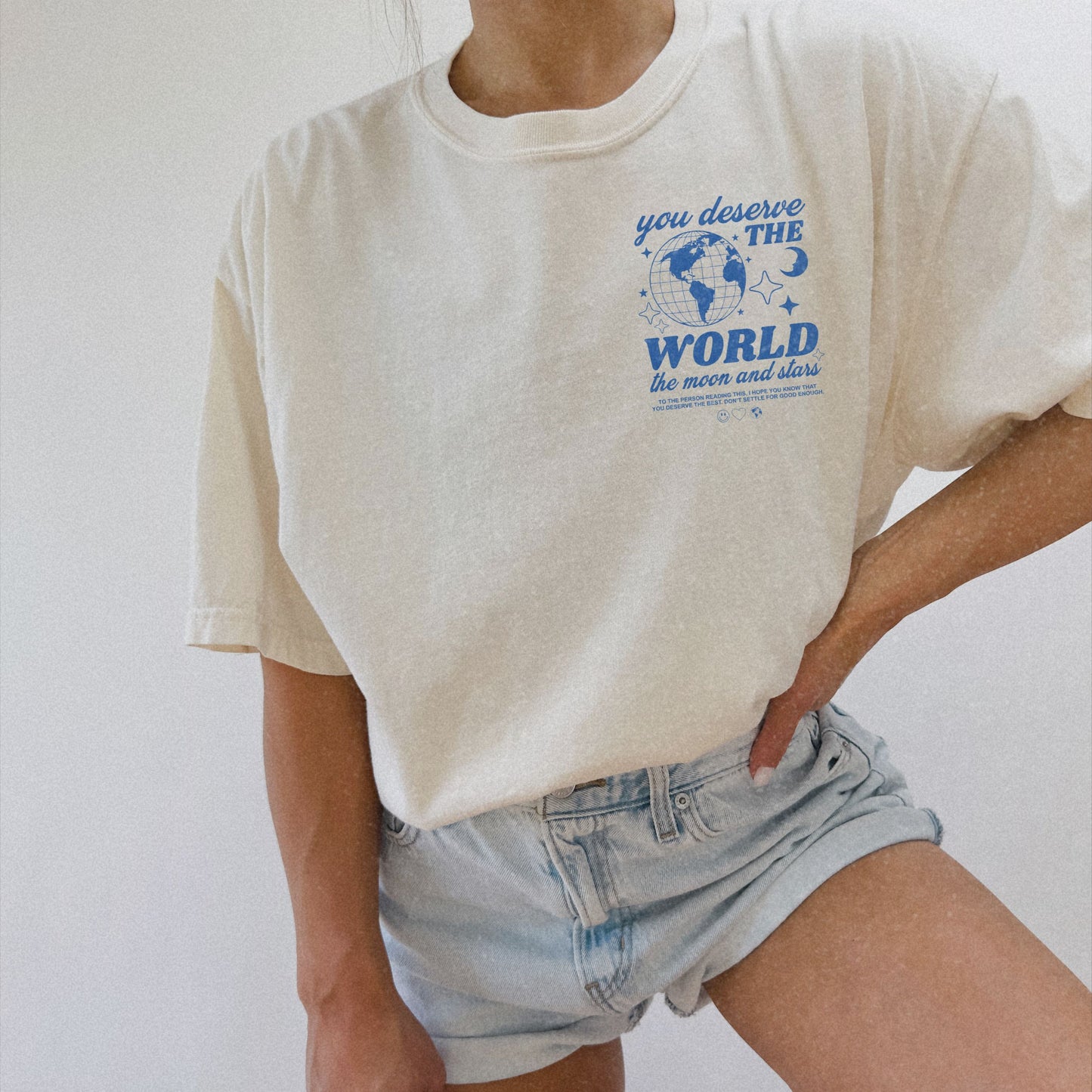 Motivational graphic t-shirt with a celestial design featuring stars, moon, and globe. Includes the inspiring phrase 'you deserve the world.' A trendy and stylish vintage-inspired tee for casual wear, perfect for spreading positivity and empowerment.